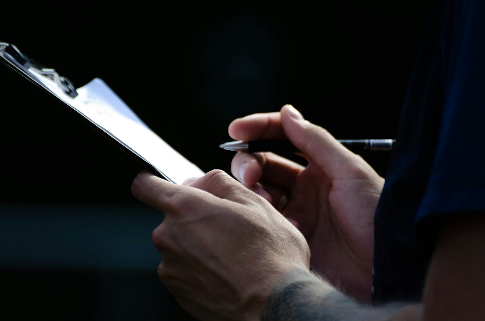Hands filling in a paper inspection checklist on a clipboard